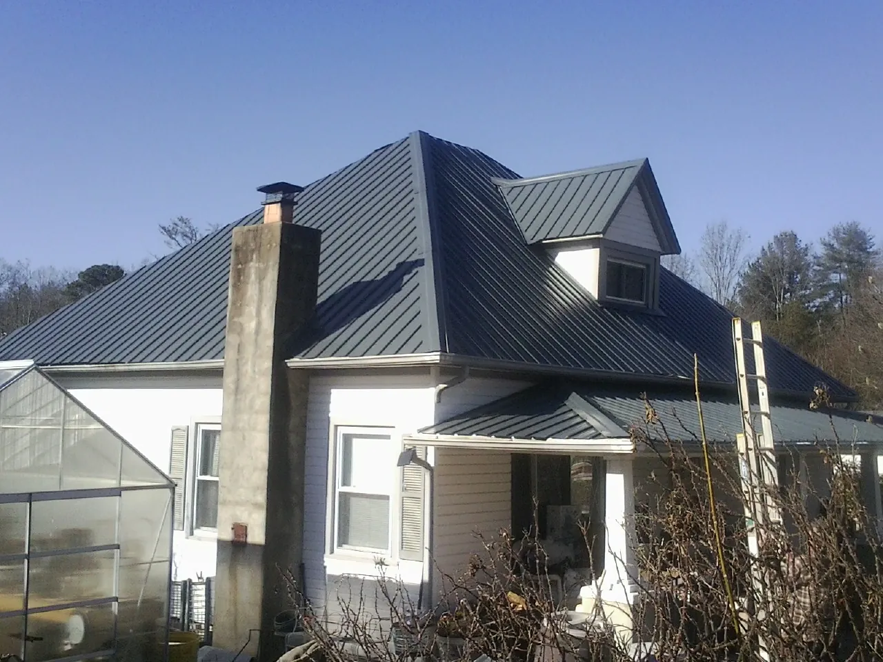 Dark blue standing seam metal roof on a white farmhouse with dormer — Slate & Tile Roof Repair by Roofing Brothers in Alice