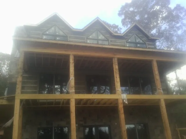 Dormers and porch framing on a large log home under construction — Roof Coating work by our crew in Alice